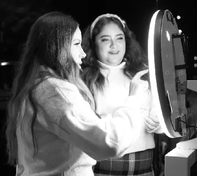 Two young women looking at a mirror in front of them.